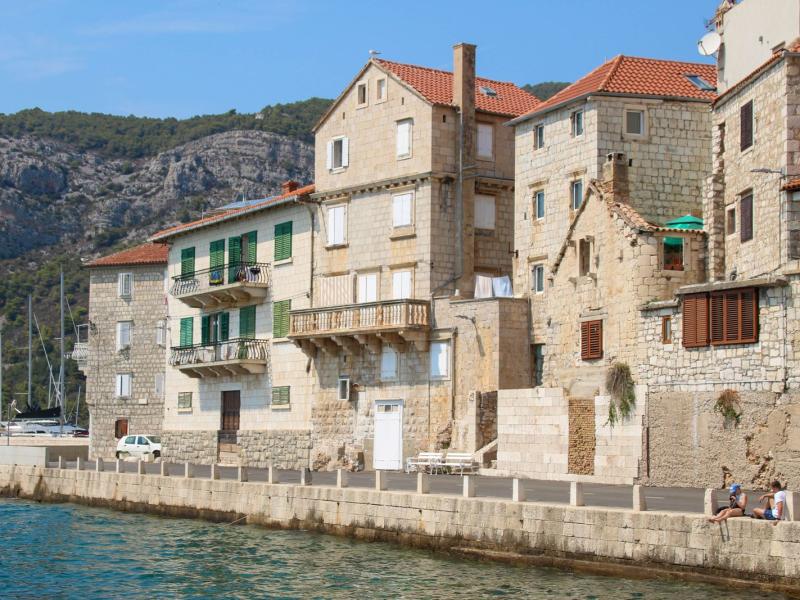Charming stone buildings along a sunlit Croatian waterfront, perfect for travel inspiration.