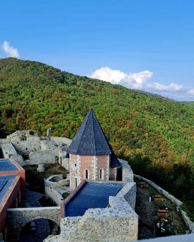 A captivating view of Medvedgrad Castle surrounded by lush hills under a bright, clear sky.
