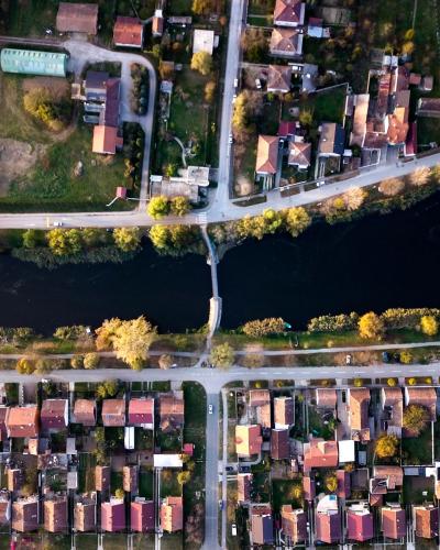 Aerial view of a neighborhood and river in Vinkovci, Croatia, showcasing houses and a bridge.