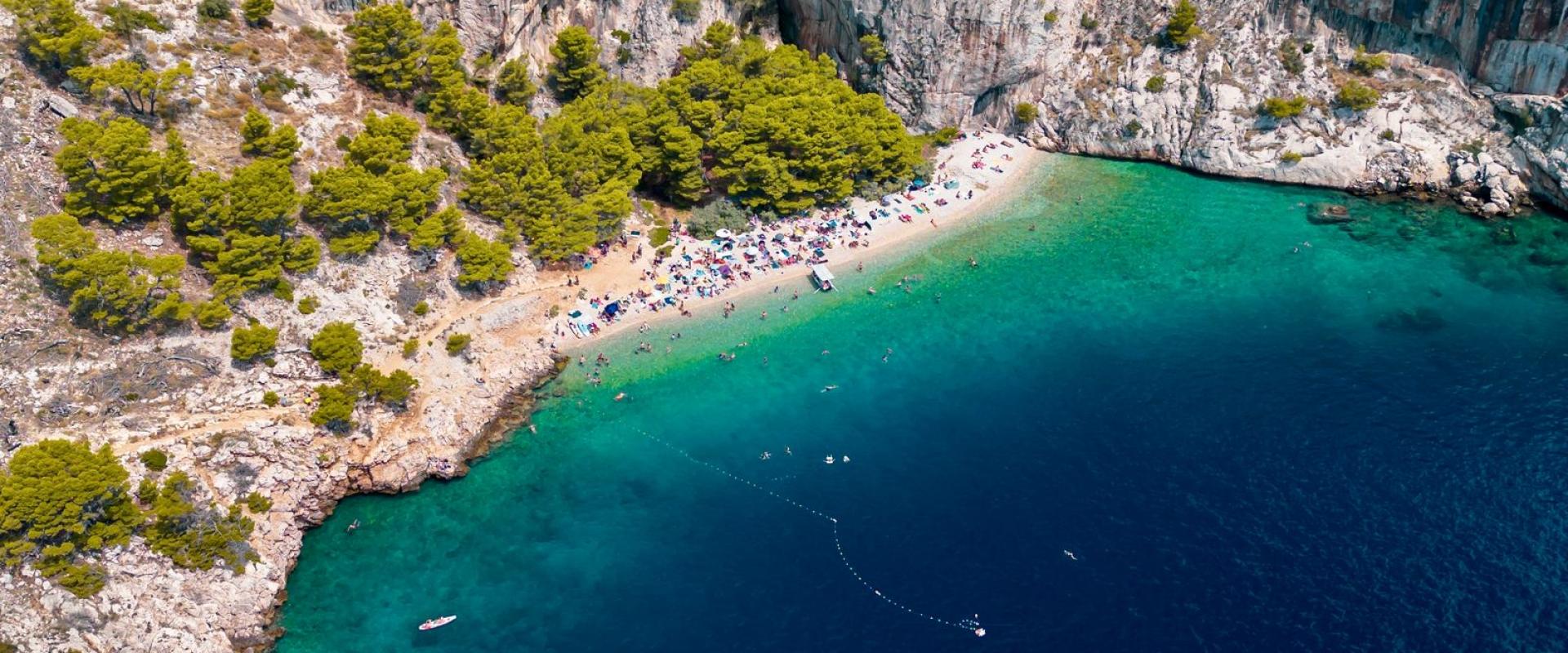 Scenic aerial view of the Split-Dalmatia County cliffs and coastline in Croatia, featuring lush greenery and turquoise waters.