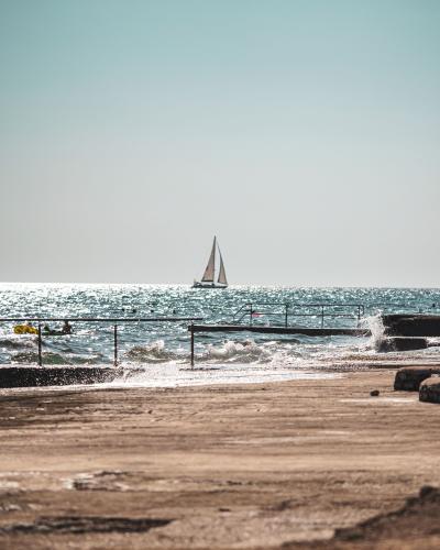 Free A tranquil view of a sailing boat on the shimmering sea under a clear sky, perfect for travel and leisure themes. Stock Photo